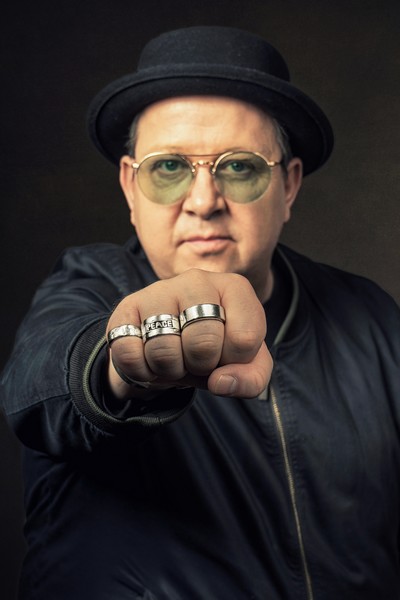 Das Bild zeigt Sebastian Krumbiegel mit geballter Faust. Auf einem Ring steht das Wort 'Peace'